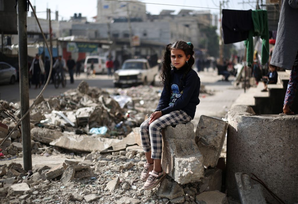 gaza orphan sitting at destroyed building